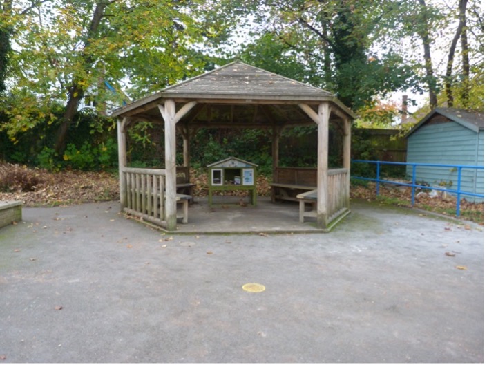 Image of a small wooden pavillon in a school playground. 
